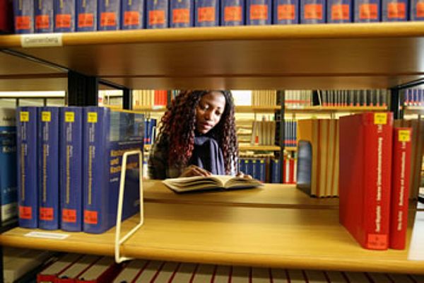 Eine junge Frau liest ein Buch in der Bibliothek